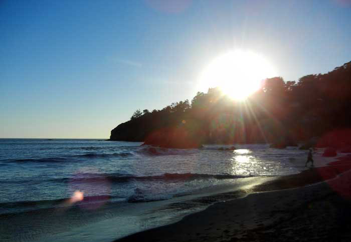 The sun sets over Muir Beach as children frolic in the water