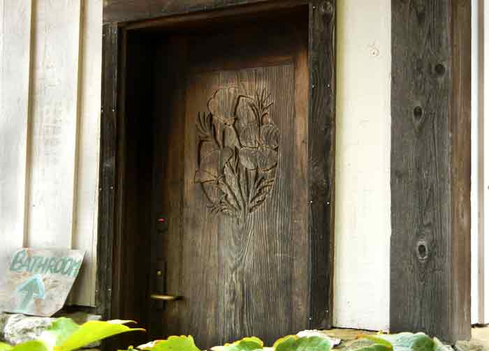 A carved wooden door adorns the building where Steven Decater build the first cookhouse on the farm at UCSC